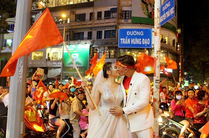 Cô dâu chú rể chụp ảnh giữa dòng người đi bão ở Trần Hưng Đạo - Nguyễn Thái Học, quận 1, TP.HCM. Ảnh: L. THOA