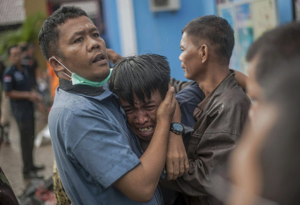 Nhân viên cứu hộ đang an ủi một người đàn ông đau đớn khi phát hiện thi thể người thân mình trong số những nạn nhân của trận sóng thần.