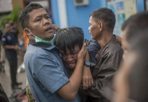 Nhân viên cứu hộ đang an ủi một người đàn ông đau đớn khi phát hiện thi thể người thân mình trong số những nạn nhân của trận sóng thần.