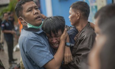 Nhân viên cứu hộ đang an ủi một người đàn ông đau đớn khi phát hiện thi thể người thân mình trong số những nạn nhân của trận sóng thần.