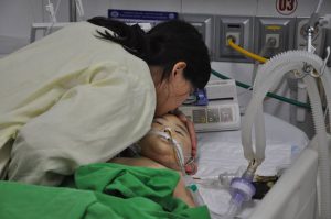 Nụ hôn tiễn biệt của người mẹ trước khi bác sĩ nhận giác mạc của bé Mai Reon. Ảnh: Hoàng Nguyễn.