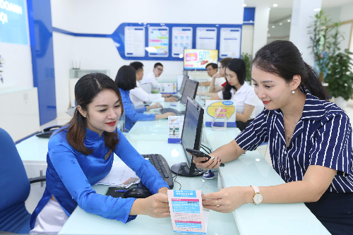 Nhân viên một nhà mạng đang hướng dẫn khách hàng thực hiện dịch vụ tại điểm giao dịch.