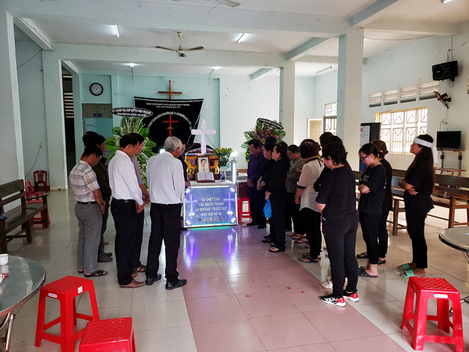 Người thân và những người trong Hội Thánh cầu nguyện trước di ảnh nạn nhân