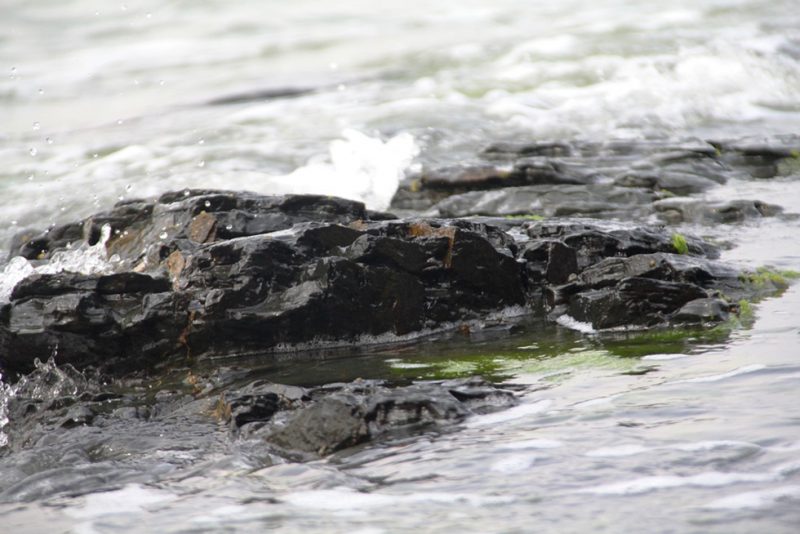 Nhiều khối đá khác lại nằm ngang với nước biển, tạo nên màu đen tuyền, lóng lánh dưới nước 