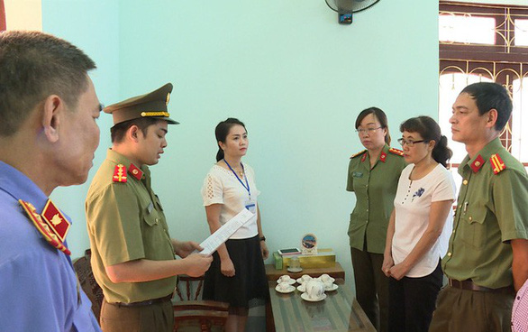Bà Nguyễn Thị Hồng Nga, chuyên viên Phòng khảo thí và quản lý chất lượng Sở GD-ĐT Sơn La (mặc áo trắng bên phải), nghe tống đạt quyết định khởi tố bị can hôm 31-7-2018 - Ảnh: Công an cung cấp