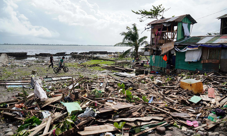 Người dân đi qua một ngôi nhà bị tàn phá ở tỉnh Leyte, miền trung Philippines hôm 25/12. Ảnh: AFP.