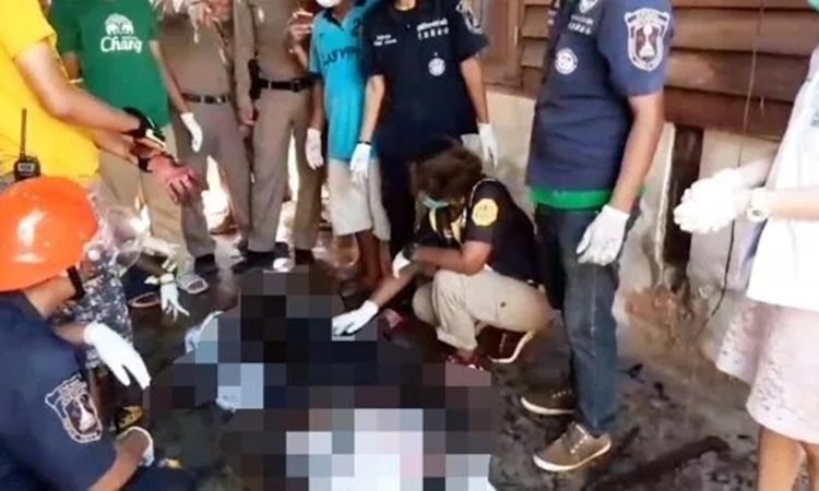 Cảnh sát, nhân viên cứu hỏa và y tế xem xét thi thể Nisachol Sawasdiwong trong ngôi nhà cháy ở tỉnh Nakhon Si Thammarat, Thái Lan hôm 26/12. Ảnh: Sun.