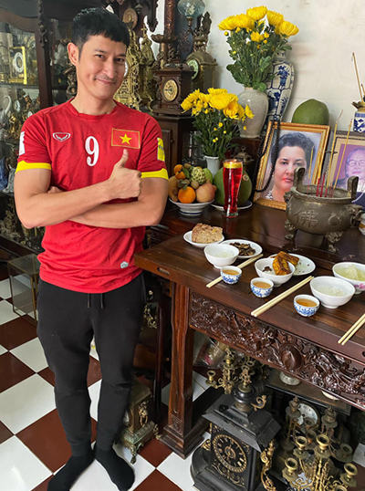 Huy Khánh cho biết hôm nay là ngày giỗ đầu của mẹ anh. Anh mặc áo đỏ sao vàng đứng bên bàn thờ muốn khoe với mẹ 90% năm nay Việt Nam lấy huy chương vàng SEA Games.
