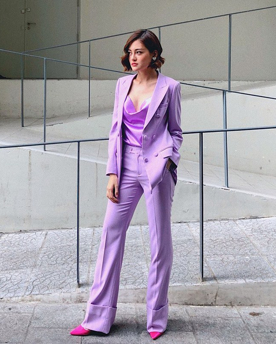 Thùy Anh chọn thêm giày hồng cánh sen nổi bật để mix cùng bộ cánh toàn sắc tím từ vest, quần suông cho đến kiểu áo cổ đổ. 