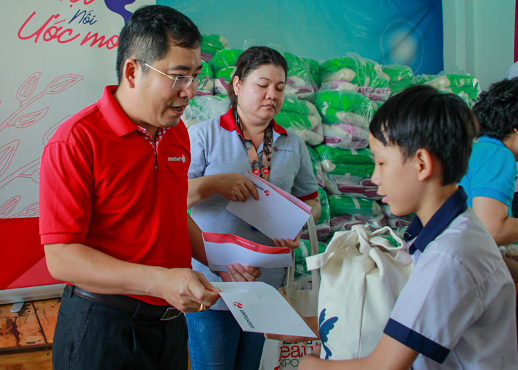 Ông Ngô Ngọc Ân, đại diện Vietlott (trái) trao quà Tết cho các em học sinh tại Trường tình thương Thiên Ân. Ảnh: Thanh Trần