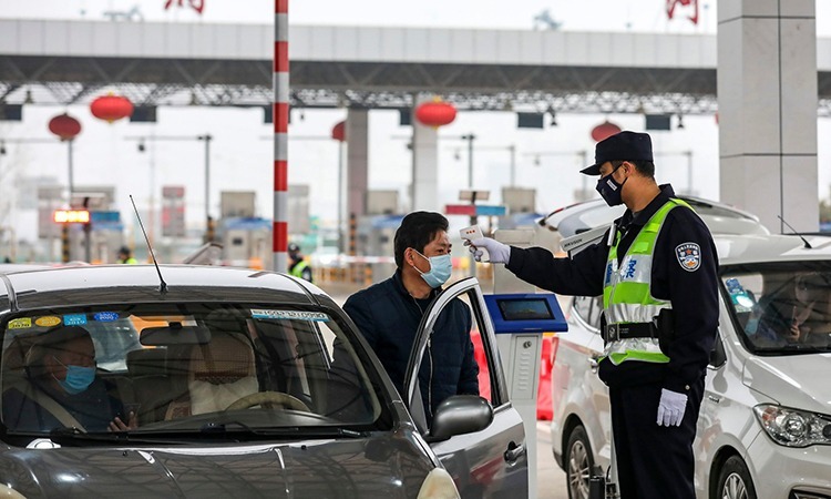 Cảnh sát Vũ Hán kiểm tra thân nhiệt của một tài xế. Ảnh: AP