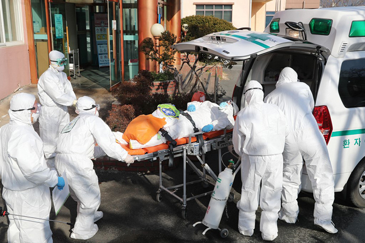 Nhân viên y tế chuyển một bệnh nhân Covid-19 từ bệnh viện Daenam đến một bệnh viện khác ở huyện Cheongdo, Hàn Quốc, hôm qua. Ảnh: AFP
