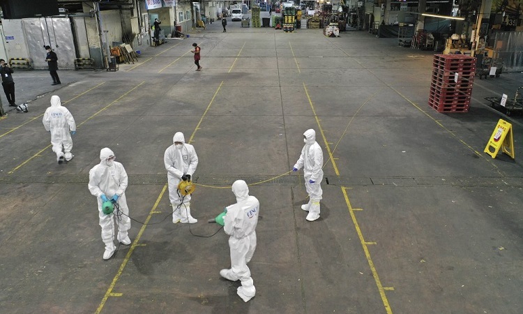 Nhân viên phòng chống dịch mặc đồ bảo hộ phun thuốc khử trùng ở thành phố Daegu, Hàn Quốc, hôm 20/2. Ảnh: AP.