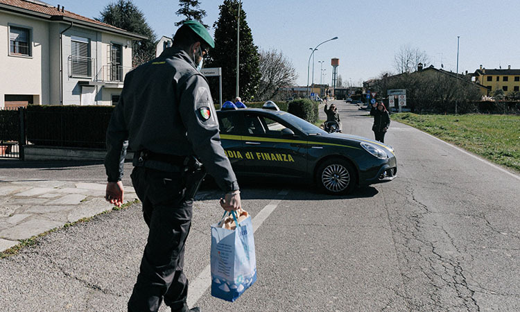 Cảnh sát tại trạm kiểm soát chuyển đồ cho người dân trong thị trấn Zorlesco thuộc vùng Lombardy, phía bắc Italy. Ảnh: NY Times.