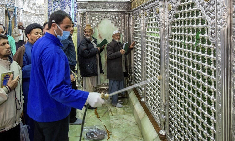 Người đàn ông phun thuốc tẩy trùng một đền thờ ở thành phố Qom, Iran, ngày 24/2. Ảnh: AP.