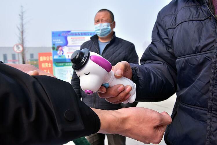Một công nhân được kiểm tra thân nhiệt trước khi vào nhà máy ở Hà Bắc (Trung Quốc). Ảnh: Reuters