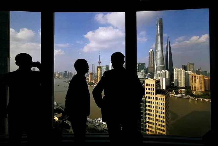 Người dân nhìn quận tài chính của Thượng Hải qua cửa kính. Ảnh: Reuters