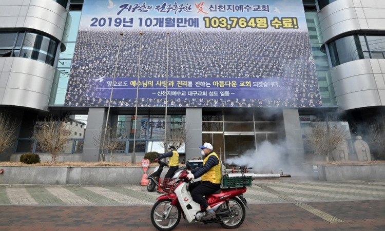 Nhân viên y tế khử trùng khu vực trước trụ sở Tân Thiên Địa ở Daegu hôm 21/2. Ảnh: AFP.