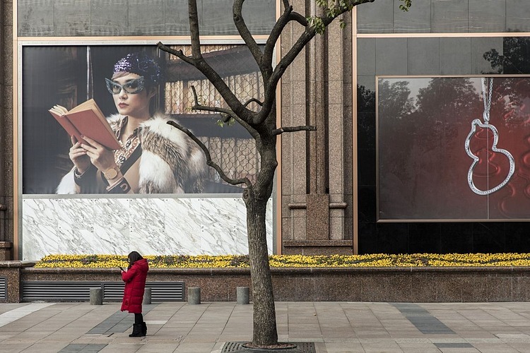 Một người phụ nữ trên đường Nam Kinh vắng lặng trong tuần này, nơi vốn là con phố thương mại sầm uất ở Thượng Hải. Ảnh: Bloomberg