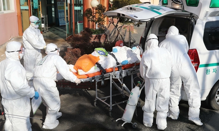 Nhân viên y tế đưa người nghi nhiễm nCoV vào bệnh viện ở Hàn Quốc ngày 21/2. Ảnh: AFP.