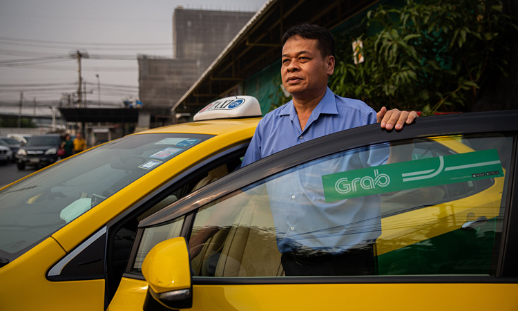 Thongsuk Thongrat đứng bên cạnh chiếc taxi của ông tại Bangkok hôm 25/2. Ảnh: NY Times.
