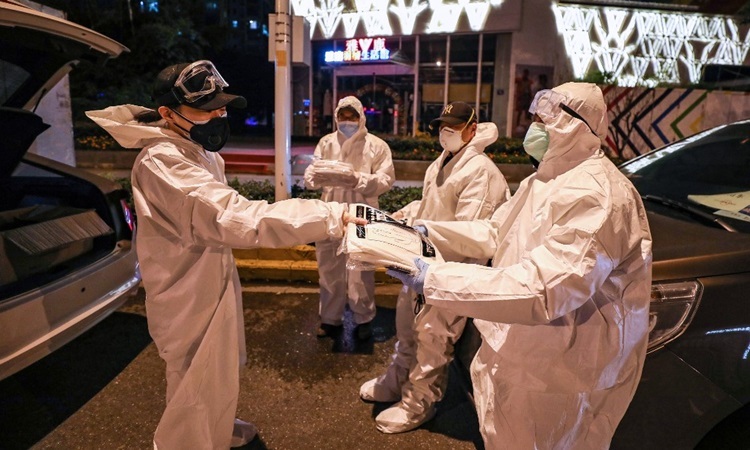 Tình nguyện viên ở Vũ Hán, tỉnh Hồ Bắc, phát đồ bảo hộ cho nhau hôm 26/2. Ảnh: AFP.