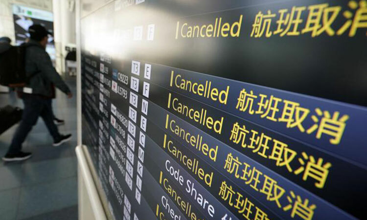 Hành khách đi qua bảng lịch trình các chuyến bay bị hủy do Covid-19 tại sân bay quốc tế Haneda ở Tokyo, Nhật Bản hôm 18/3. Ảnh: AP.