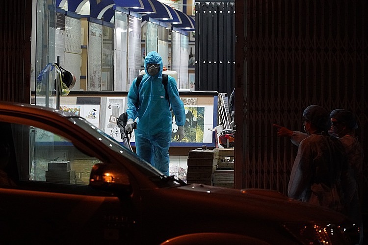 Nhân viên y tế phun thuốc khử khuẩn cửa hàng của bệnh nhân 34 tại thành phố Phan Thiết, Bình Thuận, tối 10/3. Ảnh: Việt Quốc.