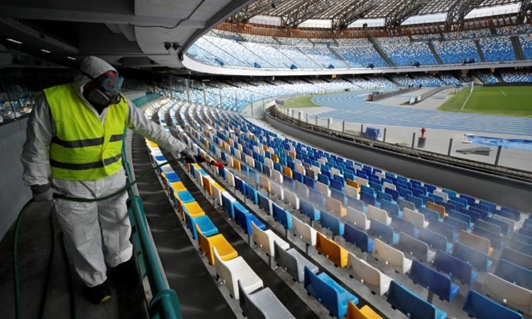Một người khử trùng ghế trong sân vận động San Paolo ở Naples ngày 4/3. Ảnh: Reuters.