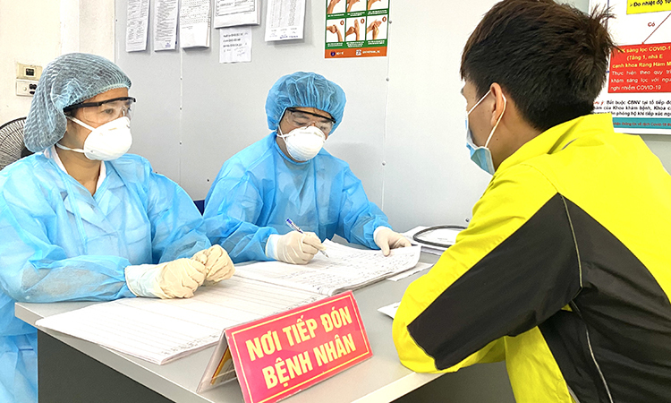 Bác sĩ bệnh viện Hà Đông đang sàng lọc người có biểu hiện ho, sốt tại phòng khám sàng lọc bệnh nhân nghi nhiễm Covid-19 sáng 22/3. Ảnh: Thùy An