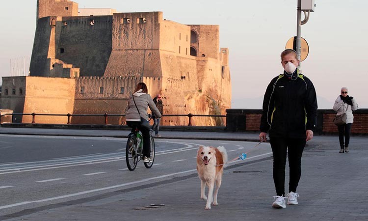 Một phụ nữ đeo khẩu trang, dắt chó đi dạo ở Naples, Italy hôm 11/3. Ảnh: Reuters.