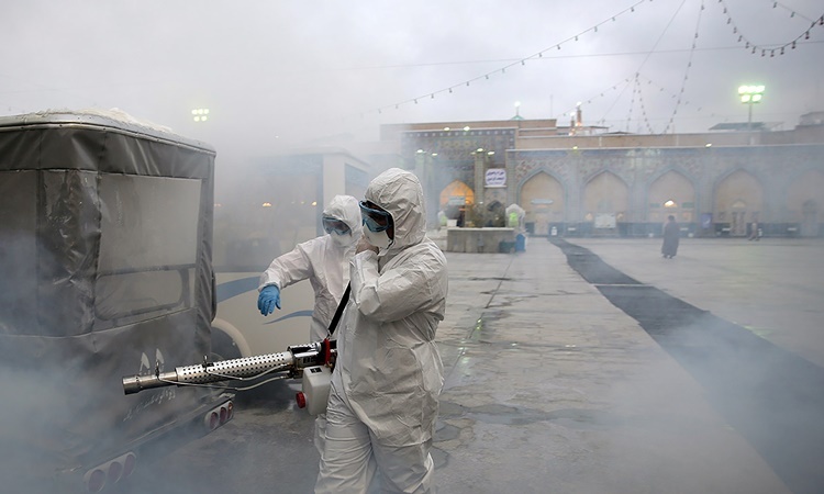 Nhân viên y tế khử trùng một ngôi đền ở Mashhad, Iran, ngày 27/2. Ảnh: Reuters.