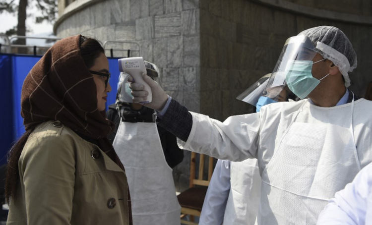 Nhân viên y tế đo thân nhiệt một người dân tại trung tâm Kabul hôm 9/3. Ảnh: AFP.