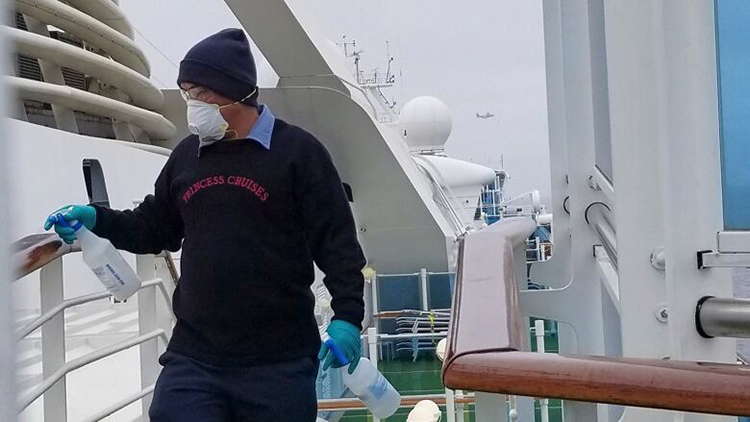 In this photo provided by Michele Smith, a cruise ship worker cleans a railing on the Grand Princess, which is currently docked off the coast of California under quarantine as passengers await test results for the coronavirus. (The Associated Press)