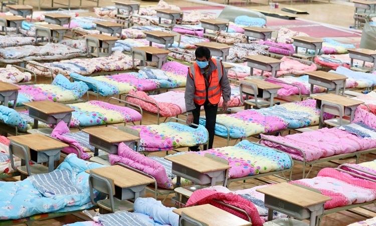 Công nhân sắp xếp giường bệnh tại một sân vận động được chuyển thành bệnh viện dã chiến ở Vũ Hán hôm 4/2. Ảnh: Reuters.