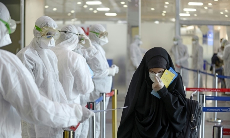 Nhân viên y tế phát tờ thông tin phòng dịch cho hành khách đến từ Iran tại sân bay Najaf ở Iraq ngày 5/3. Ảnh: AFP.