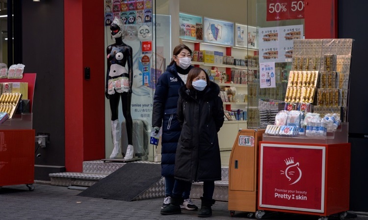 Nhân viên bán hàng đeo khẩu trang đứng bên ngoài cửa hiệu mỹ phẩm ở thủ đô Seoul của Hàn Quốc hôm nay. Ảnh: AFP.
