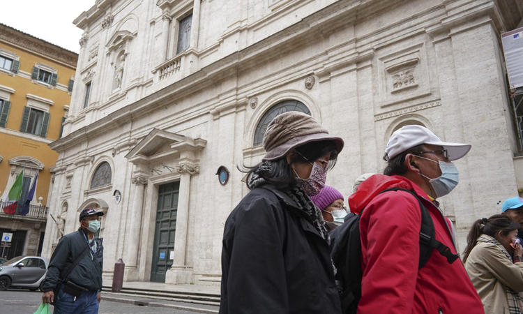 Hai du khách (phải) đeo khẩu trang đứng bên ngoài nhà thờ St. Louis ở Rome hôm 1/3. Ảnh: AP.