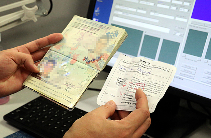Công an cửa khẩu Nội Bài kiểm tra phiếu khai báo y tế được kiểm tra và đóng dấu của khách nước ngoài hôm 11/3. Ảnh: Bá Đô