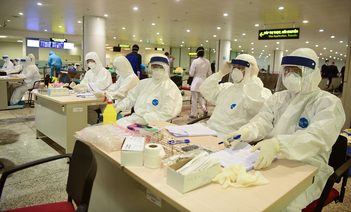 Các nhân viên y tế trực lấy mẫu bệnh phẩm khách nhập cảnh sân bay Nội Bài để xét nghiệm nCoV. Ảnh: Giang Huy.