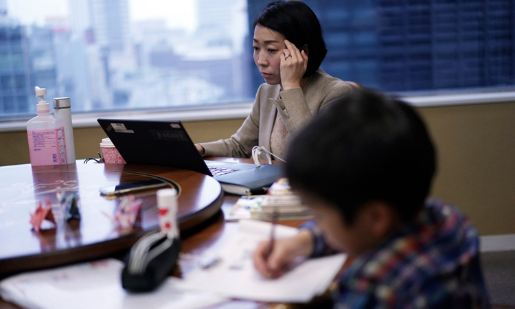 Một phụ huynh làm việc trong lúc con của cô làm bài tập tại Tokyo, Nhật Bản hôm 2/3. Ảnh: AP.