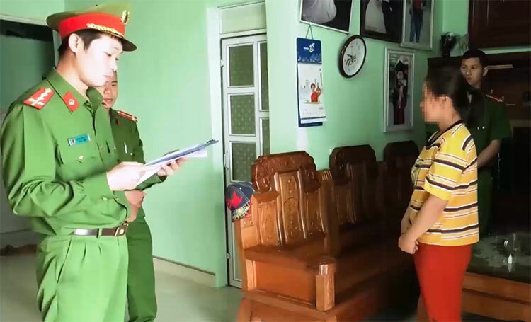 Vợ Thông (áo vàng) nghe cảnh sát đọc lệnh khởi tố chồng. Ảnh: C.A