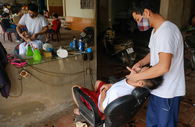 Hiệu cắt tóc của anh Tuấn đón vị khách đầu tiên sau gần một tháng toàn xã bị cách ly.