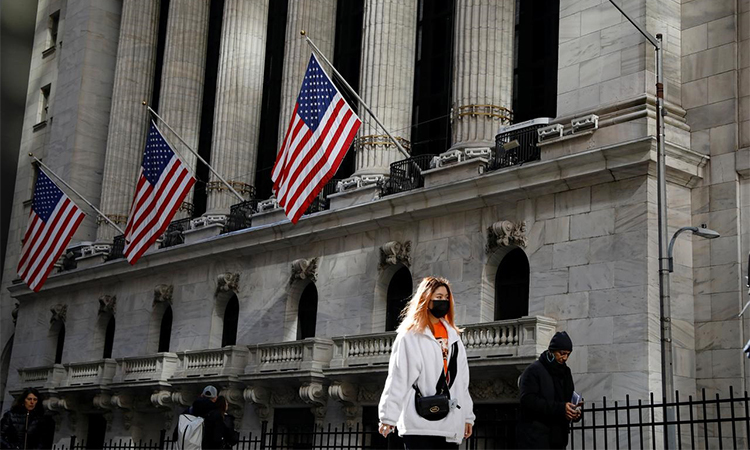 Một phụ nữ đeo khẩu trang khi đi qua Sở giao dịch chứng khoán New York, New York, Mỹ hôm 4/3. Ảnh: Reuters.
