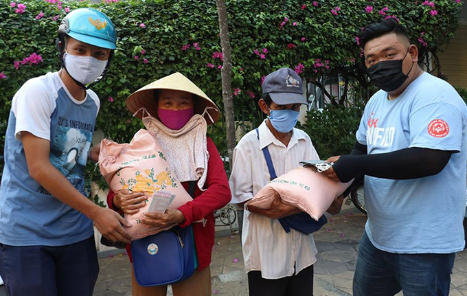 Tình nguyện viên tặng quà cho người bán vé số ở quận Ninh Kiều. Ảnh: Hưng Lợi