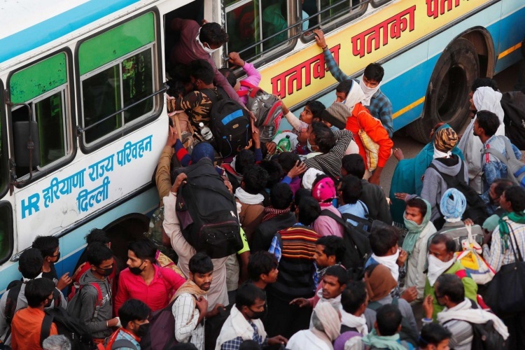 Người dân Ấn Độ chen chúc lên xe bus ở ngoại ô New Delhi,  ngày 29/3, để về quê sau lệnh phong toả. Ảnh: Reuters.