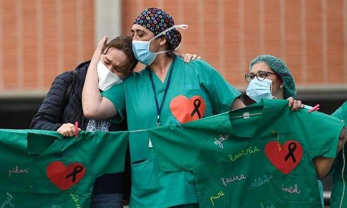 Nhân viên y tế Tây Ban Nha an ủi vợ của một nam y tá tử vong do nCoV tại bệnh viện gần Madrid hôm 10/4. Ảnh: AFP.