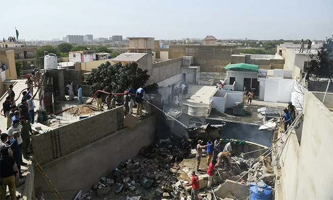 Lực lượng cứu hộ xịt nước vào mảnh vỡ của chiếc máy bay lao xuống khu dân cư ở Karachi, Pakistan, ngày 22/5. Ảnh: AFP.