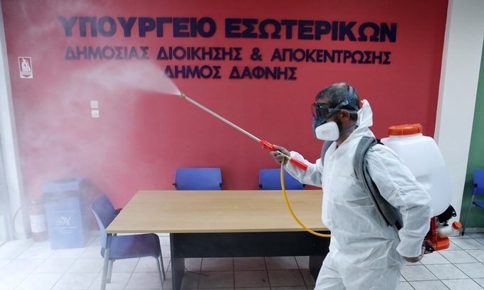 Nhân viên trong trang phục bảo hộ phun chất khử trùng tại một phòng tiếp dân ở khu ngoại ô Dafni, phía đông thủ đô Athens, Hy Lạp, ngày 9/3. Ảnh: AP.
