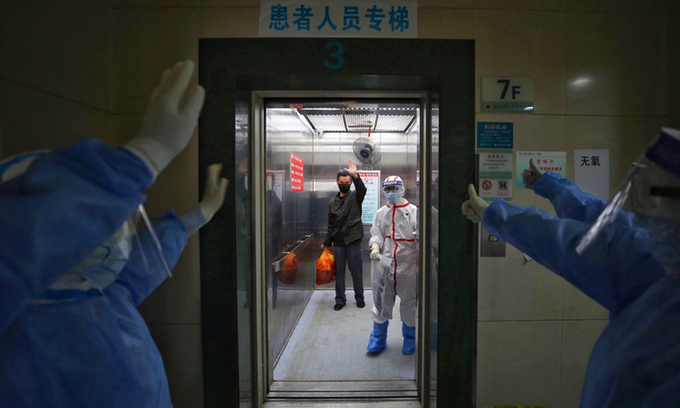 Nhân viên y tế vẫy tay chào bệnh nhân Covid-19 xuất viện tại Bệnh viện Hội Chữ thập đỏ Vũ Hán, hồi tháng 3. Ảnh: AFP.